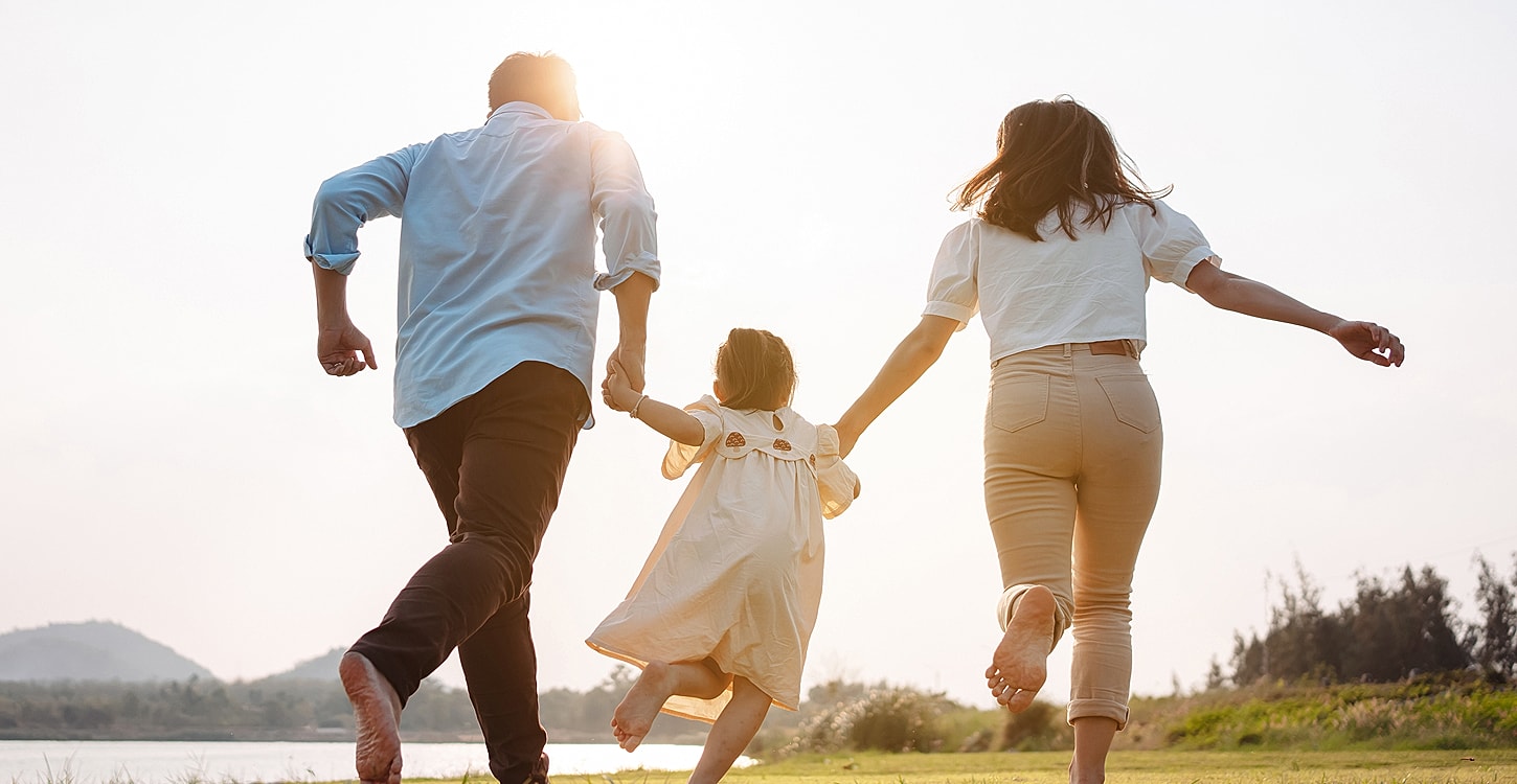 Family joyfully running together by the lake.