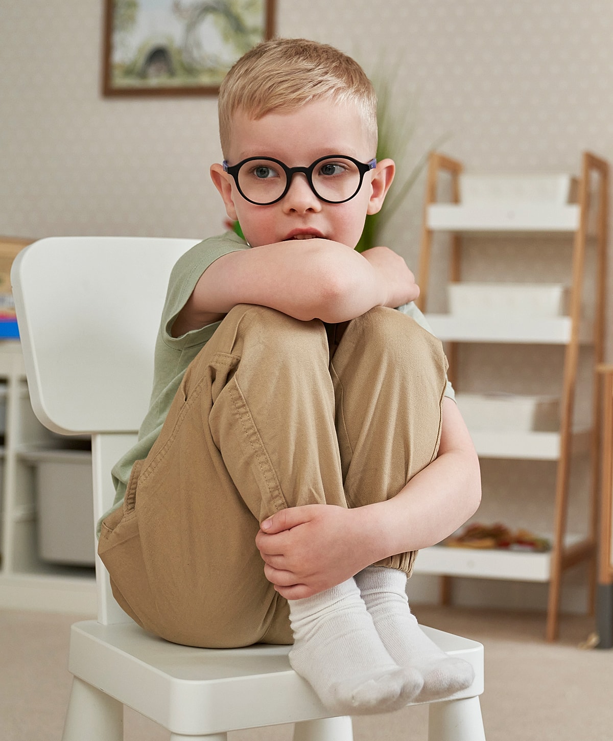 Boy sitting on a chair, looking thoughtful.