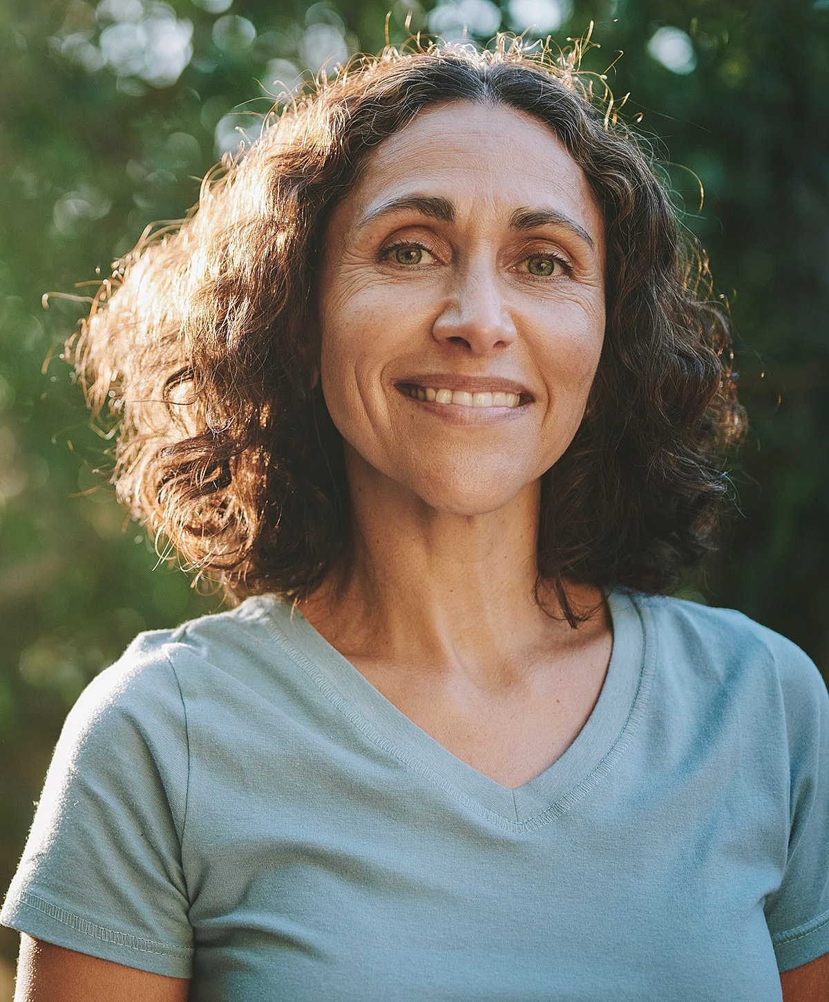 Smiling woman with curly hair outdoors.