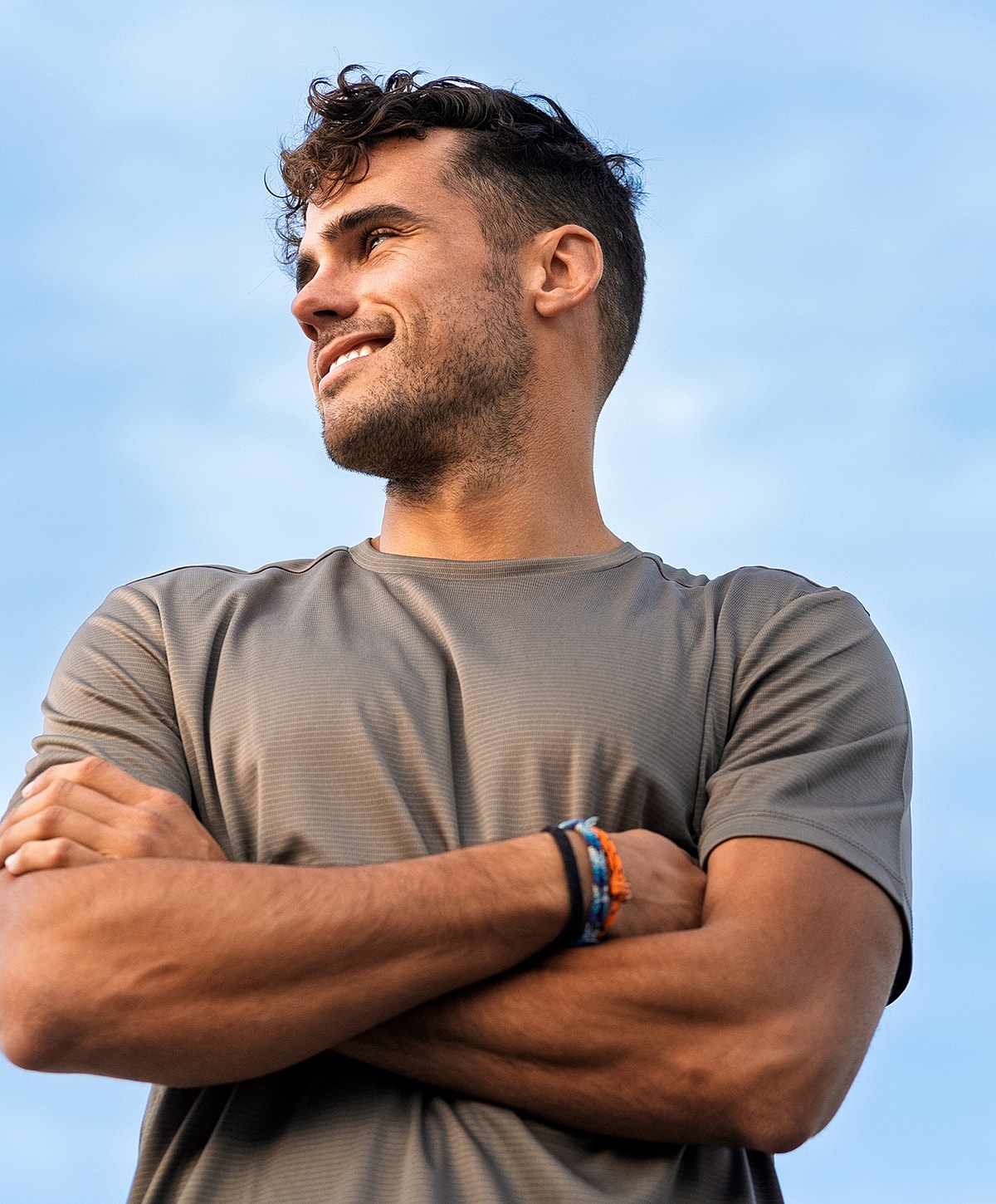 Smiling man with crossed arms and athletic shirt.