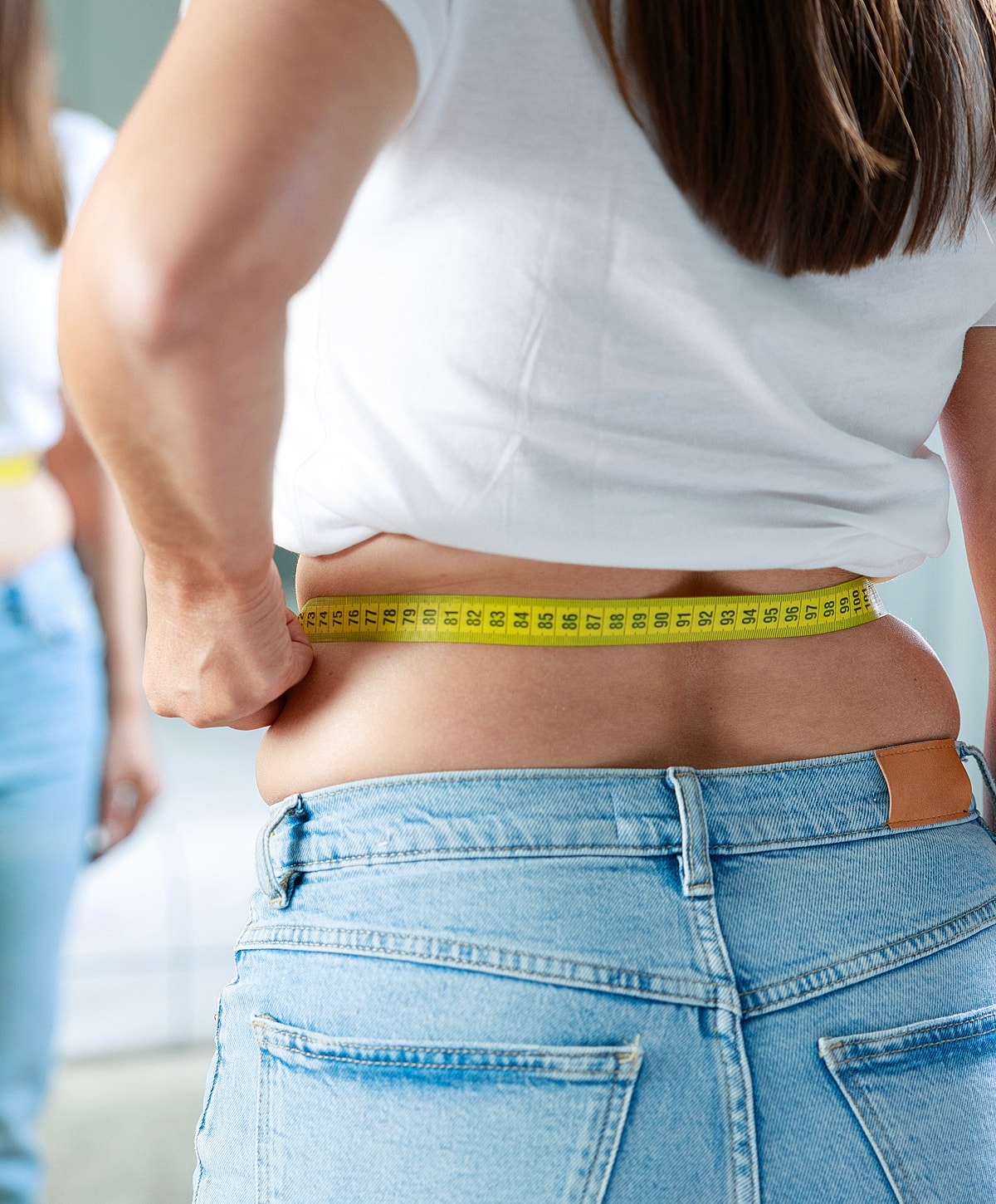 Measuring waist with a tape measure in mirror.