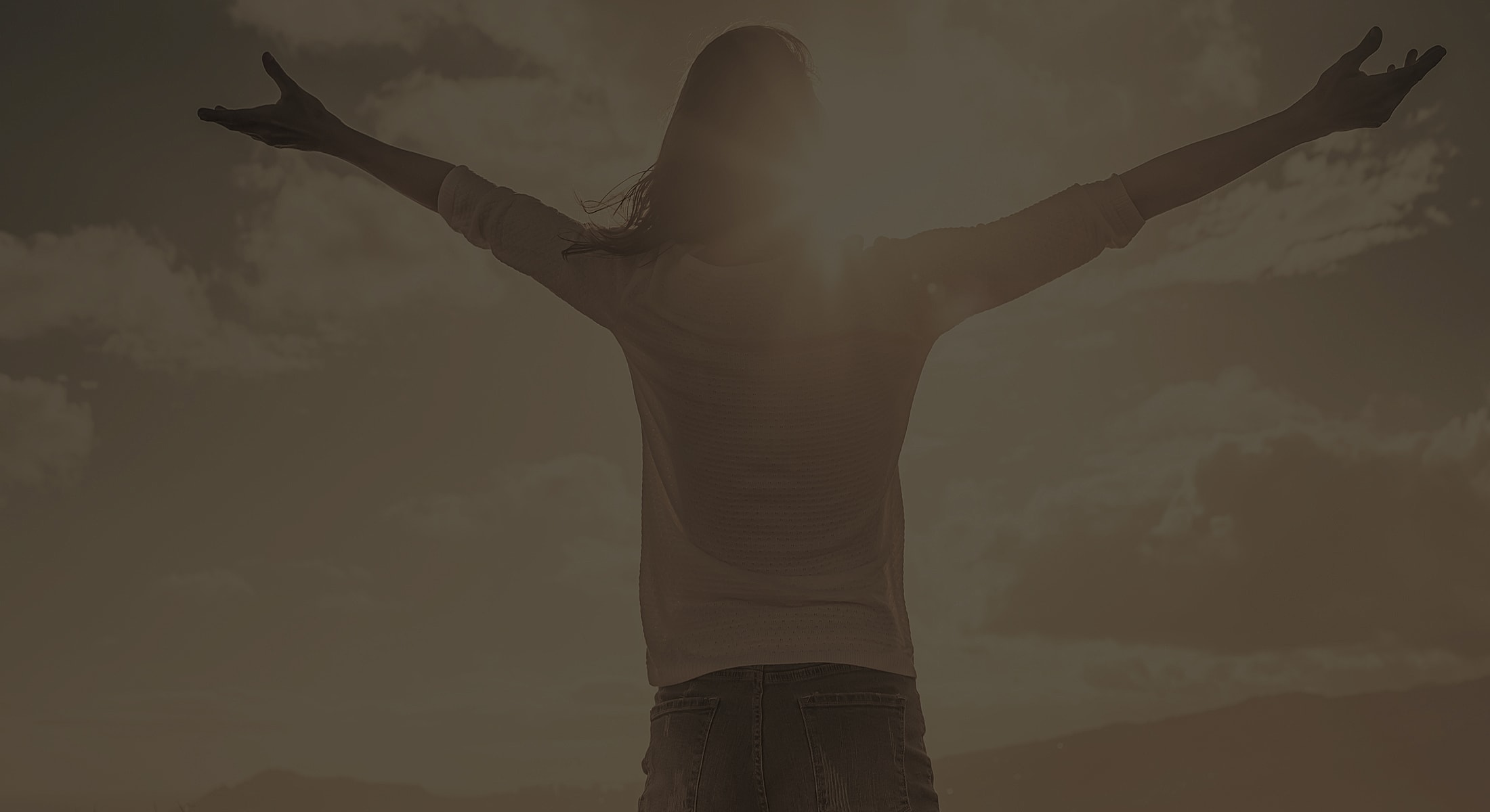 Person enjoying a sunset with open arms.