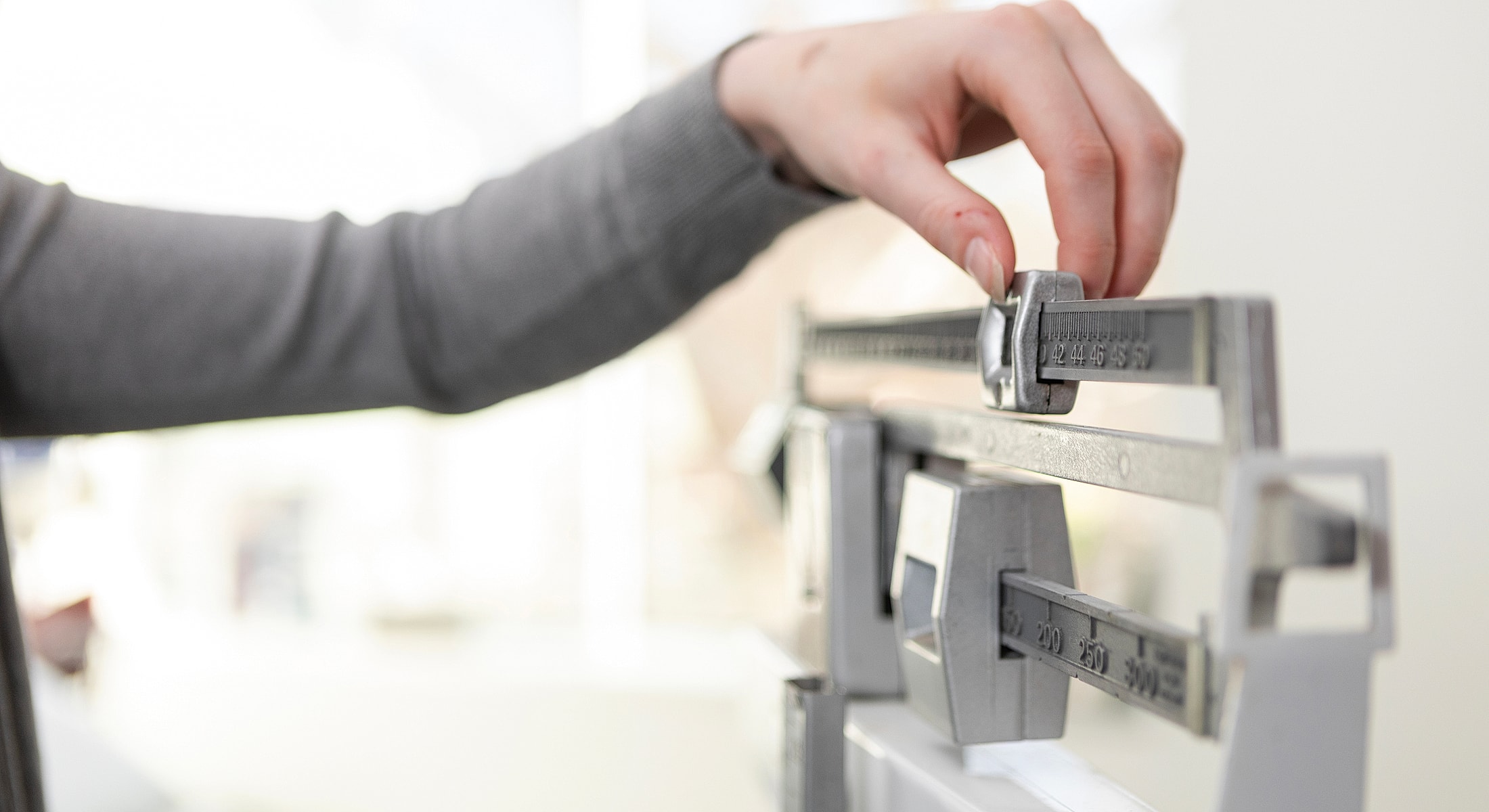 Person adjusting weights on a balance scale.